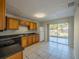 Bright kitchen with wood cabinets, tile flooring, stainless sink, and sliding glass doors leading to the backyard at 7861 Copperfield Ct, Orlando, FL 32825