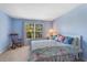 Light-filled bedroom with floral bedding, rocking chair, and a bright window with outdoor views at 8606 Terrace Pines Ct, Orlando, FL 32836