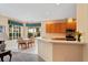 Sunlit eat-in kitchen features wood cabinets, a breakfast bar, and a window with green and blue valance overlooking the front yard at 8606 Terrace Pines Ct, Orlando, FL 32836