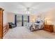 Comfortable main bedroom with large windows dressed with blue curtains, a ceiling fan, carpet floors, and wood furniture at 8606 Terrace Pines Ct, Orlando, FL 32836