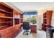 Home office featuring custom built-in wooden shelving, drawers, and a desk with a cozy chair at 8606 Terrace Pines Ct, Orlando, FL 32836