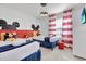 Whimsical bedroom with two twin beds, Mickey Mouse decor, and red and white striped curtains at 8907 Sydney Ave, Kissimmee, FL 34747