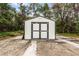 A white shed with a gray trim and double doors provides additional storage on the property at 8908 Turnberry Ct, Orlando, FL 32819