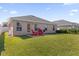 Backyard view of patio with red chairs, well-maintained lawn, and exterior elevation of the home at 1200 Kellogg Dr, Tavares, FL 32778