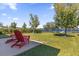 Backyard featuring a well-manicured lawn, patio with red chairs, and lake views at 1200 Kellogg Dr, Tavares, FL 32778