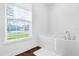 Bathtub in a neutral-toned bathroom featuring a large window and sleek, modern fixtures at 1200 Kellogg Dr, Tavares, FL 32778