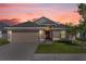 Charming single-story home at dusk featuring a two-car garage and well-manicured lawn at 1200 Kellogg Dr, Tavares, FL 32778