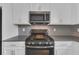 Stainless steel oven and microwave compliment the modern kitchen with white cabinets and gray backsplash at 1616 Oak Blossom Dr, Davenport, FL 33837