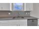 Stainless steel sink and appliances compliment this modern kitchen with white cabinets and gray backsplash at 1616 Oak Blossom Dr, Davenport, FL 33837