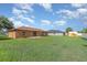 Large backyard with lush green grass and a view of the home's rear exterior at 1644 Piccadilly Dr, Daytona Beach, FL 32117
