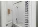 Clean, well-lit bathroom with a shower-tub combo, white tiling, and a white and blue striped shower curtain at 16613 Caribbean Breeze Way # 34714, Clermont, FL 34714