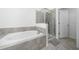 Bathroom showcasing a soaking tub with tiled surround and glass-enclosed shower at 171 Bogey Dr, Davenport, FL 33896