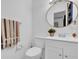 Clean bathroom featuring a white vanity, round mirror, toilet, and towel rack, providing essential amenities at 1868 Wayside Dr, Orlando, FL 32818
