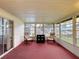 Enclosed sunroom featuring two chairs, red carpet, large windows, and natural light at 200 Patricia Pl, Davenport, FL 33897