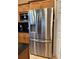 Stainless steel French door refrigerator with water dispenser, located near wooden cabinetry with black countertops at 203 Flounder Pl, Kissimmee, FL 34759