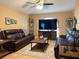 Inviting living room with tile floors, leather sofas, ceiling fan, and large television set for entertainment at 203 Flounder Pl, Kissimmee, FL 34759