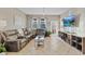 Cozy living room with leather furniture, a large TV, and plenty of natural light from the windows at 3320 Grande Heron Dr, Harmony, FL 34773