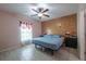 Cozy bedroom with wood accent wall, ceiling fan, and neutral-toned floor tiles at 3797 Briarwood Estates Cir, St Cloud, FL 34772