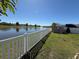 Scenic pond view with a white fence, lush green grass, and a tranquil water feature at 3797 Briarwood Estates Cir, St Cloud, FL 34772