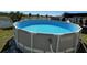A round Intex pool is filled with blue water and situated in a green backyard near a lake at 3797 Briarwood Estates Cir, St Cloud, FL 34772
