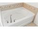 A close-up of a soaking tub with mosaic tile accents, and a brushed nickel faucet at 625 Silverthorn Pl, Groveland, FL 34736