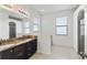 Bathroom with double sinks, granite counters, dark cabinets, natural light, and tile floor at 625 Silverthorn Pl, Groveland, FL 34736