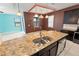 An oversized kitchen island with stainless steel sink, granite countertops, dark cabinets and pendant lights at 625 Silverthorn Pl, Groveland, FL 34736
