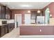 A spacious kitchen with stainless steel appliances, dark cabinets, and granite countertops, with access to laundry room at 625 Silverthorn Pl, Groveland, FL 34736