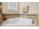 Bathroom showcasing a luxurious soaking tub with tile surround and a window providing natural light at 7135 Ticklegrass St, Winter Garden, FL 34787