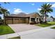 Well-manicured home with a brick driveway, three-car garage and verdant lawn under a bright blue sky at 7135 Ticklegrass St, Winter Garden, FL 34787