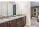 Bathroom with double sinks, granite countertop, dark wood cabinets, and a door that leads to a bedroom at 7568 Marker Ave, Kissimmee, FL 34747