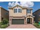Charming two-story home featuring a stone facade, a two-car garage, and a well-manicured lawn at 7568 Marker Ave, Kissimmee, FL 34747