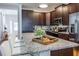 An open-concept kitchen with stainless appliances, granite countertops, dark wood cabinets and breakfast bar at 7568 Marker Ave, Kissimmee, FL 34747
