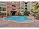 Relaxing community pool surrounded by a red brick deck, tropical landscaping, and views of the buildings at 911 N Orange Ave # 104, Orlando, FL 32801