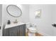 Elegant powder room features a gray vanity with gold hardware, round mirror, and light wood floor at 10236 Chorlton Cir, Orlando, FL 32832