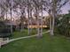 A backyard featuring a sprawling lawn, mature trees, and a charming path leading to the waterfront at 10411 Hart Branch Cir, Orlando, FL 32832