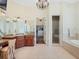 A bathroom with granite countertops, a walk-in shower, a standalone bathtub, and a chandelier at 10411 Hart Branch Cir, Orlando, FL 32832
