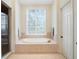 A spacious bathroom with a tiled standalone tub, a glass-enclosed shower, and natural light from a window at 10411 Hart Branch Cir, Orlando, FL 32832