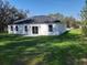 View of the house's back exterior with sliding glass doors and a lush green lawn at 12793 Sw 43Rd Cir, Ocala, FL 34473