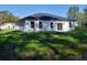 Back exterior view of the home with a dark roof, sliding glass doors, and a manicured lawn at 12793 Sw 43Rd Cir, Ocala, FL 34473