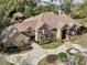 Expansive aerial view of a brick home with a tile roof, circular driveway, manicured landscaping, and mature trees at 1500 Whitstable Ct, Lake Mary, FL 32746