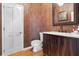 Half-bath featuring wallpaper, hardwood floors, wood vanity, and a white door at 1500 Whitstable Ct, Lake Mary, FL 32746