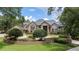 Elegant brick home with lush front yard landscaping, brick retaining wall, and large trees at 1500 Whitstable Ct, Lake Mary, FL 32746