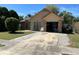 Inviting home exterior with a well-manicured lawn, mature trees, and attached garage at 1663 Sunburst Way, Kissimmee, FL 34744