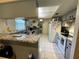 Functional kitchen with white appliances, tile floors, and a breakfast bar overlooking the adjacent room at 1663 Sunburst Way, Kissimmee, FL 34744