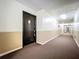 Long hallway with neutral colors, and brown carpet leading to a black door to unit E-1 at 1695 Lee Rd # E205, Winter Park, FL 32789