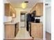 Efficient kitchen with tiled floor, black appliances, light wood cabinets, and in unit washer/dryer at 1695 Lee Rd # E205, Winter Park, FL 32789