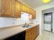 View of the kitchen sink and wood cabinets, along with a peek at in-unit laundry at 1695 Lee Rd # E205, Winter Park, FL 32789