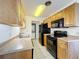 Efficient kitchen featuring wood cabinets, black appliances, and tile flooring for easy maintenance at 1695 Lee Rd # E205, Winter Park, FL 32789