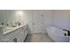 Bright bathroom features a double sink vanity, soaking tub, tiled floor and modern fixtures for a spa-like experience at 18410 Blue Heron Cir, Deer Island, FL 32778